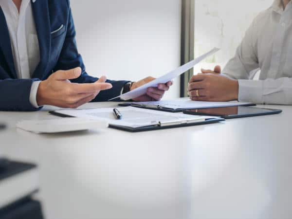 Two people sitting at a table with one explaining insurance to the other